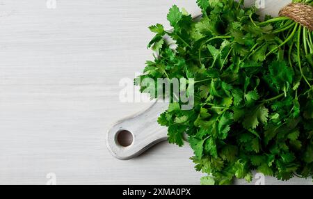 Un mucchio di coriandolo fresco, su un tavolo di legno bianco, da vicino, vista dall'alto, niente persone Foto Stock