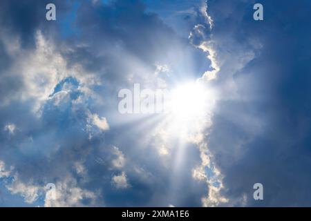 Nuvole piovose con il sole che splende, raggi di sole, cielo blu Foto Stock