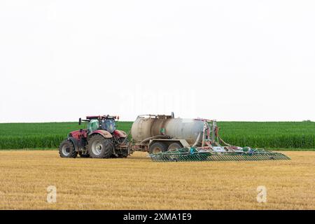 Agricoltore che spande concime liquido sul campo di grano raccolto, Svevia Alb, Baden-Wuerttemberg, Germania Foto Stock