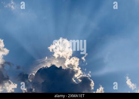 Nuvole piovose con il sole che splende, raggi di sole, cielo blu Foto Stock