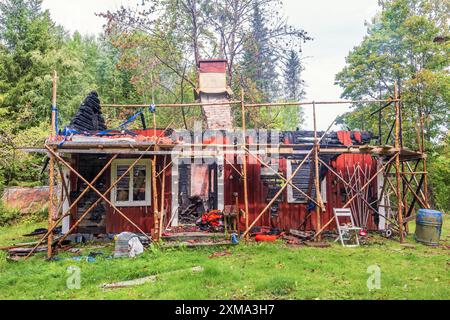 Rosso idilliaco vecchio cottage in legno che è bruciato nella foresta, in Svezia Foto Stock