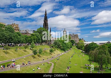 Parco urbano con persone sedute sull'erba e edifici storici sullo sfondo sotto un cielo blu Foto Stock