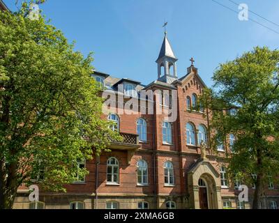 Grande edificio in mattoni con torre, finestre e circondato da alberi verdi, esbjerg, danimarca Foto Stock