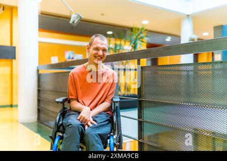 Uomo felice con paralisi cerebrale in un coworking moderno sorridente alla telecamera nel corridoio Foto Stock