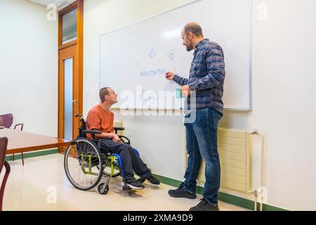 Uomo con paralisi cerebrale e collega che usa il tabellone durante il brainstorming in un moderno coworking Foto Stock