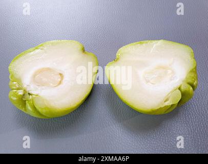 Due metà di un chuchu verde con carne bianca visibile su sfondo grigio, chayote, verdure, Algarve, Portogallo Foto Stock