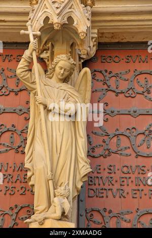 Scultura dell'Arcangelo Michele con lancia e croce sul portale della Vergine Maria, portale della chiesa gotica con arredi e iscrizioni, dettaglio Foto Stock