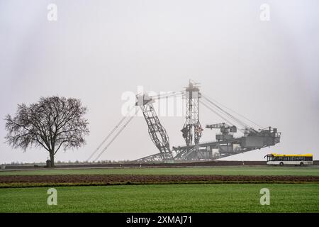 Escavatore minerario presso la miniera di lignite a cielo aperto Garzweiler II presso l'ex villaggio demolito di Luetzerath, sulla strada di campagna L12, nella nebbia Foto Stock