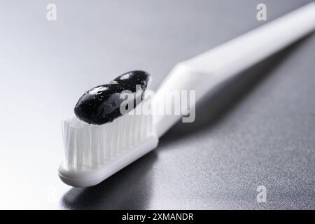 Vista ravvicinata del dentifricio nero al carbone su uno spazzolino da denti Foto Stock