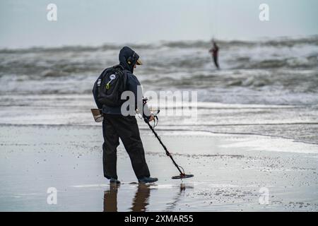 Cacciatore di tesori, uomo con metal detector sulla spiaggia, nuvole di tempesta scure, autunno nel Mare del Nord nell'Olanda settentrionale, vicino a Egmond aan Zee, Paesi Bassi Foto Stock