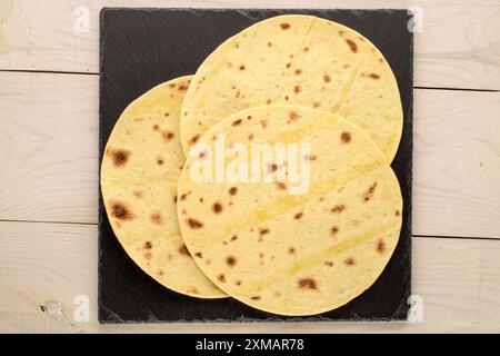 Tre gustosi tacos con ardesia su tavolo in legno, macro, vista dall'alto. Foto Stock