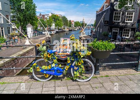 Sint Antoniesluis, sul canale Oudeschans, bicicletta decorata con girasoli, barca da crociera sul canale, caffetteria, De Sluyswacht, Amsterdam, paesi Bassi Foto Stock