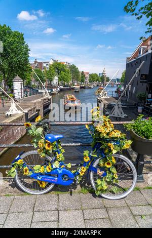 Sint Antoniesluis, sul canale Oudeschans, bicicletta decorata con girasoli, barca da crociera sul canale, caffetteria, De Sluyswacht, Amsterdam, paesi Bassi Foto Stock