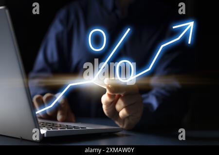 Grafico di crescita finanziaria che mostra le frecce di investimento sullo schermo di un notebook tenuto da un giovane uomo caucasico nella foto del concetto di business. Foto Stock