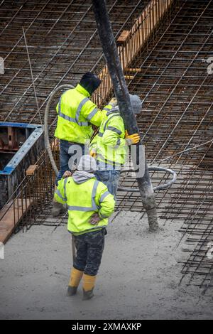 Cantiere, calcestruzzo, le fondamenta di un edificio sono cementate, il calcestruzzo viene pompato sui tappetini in cemento armato Foto Stock