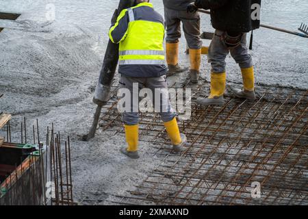 Il cantiere, il cemento, il pavimento e il soffitto di un edificio sono in cemento, il cemento viene pompato sui tappetini in cemento armato Foto Stock