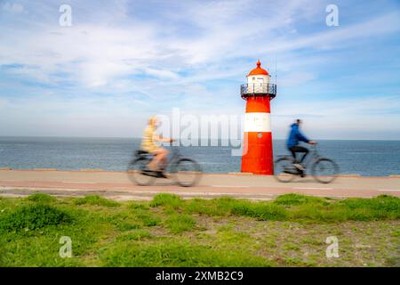 Diga del Mare del Nord vicino a Westkapelle, faro di Westkapelle Laag, ciclisti sulla pista ciclabile Zeeuwse Wind Route, provincia della Zelanda, Walcheren Foto Stock