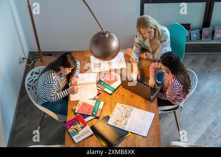 Homeschooling, durante il blocco nel gennaio 2021, la madre aiuta le sue due figlie, a casa, a imparare, con libri di testo e computer, chiusure scolastiche Foto Stock