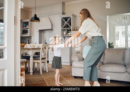 Madre, figlia e tenendosi per mano ballando in casa per la canzone preferita, insegnando a muovere e legare in salotto. Famiglia felice, donna e ragazza per Foto Stock
