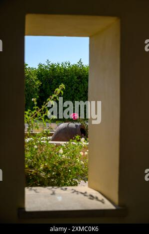 Una finestra giardino che si affaccia su un lussureggiante giardino con fiori e un grande vaso. Il lussuoso edificio dell'Aphrodite Hills Hotel and Resort con splendidi giardini Foto Stock