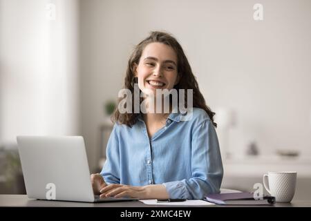 Giovane donna attraente seduta alla scrivania con un moderno laptop Foto Stock