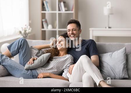 I coniugi felici si divertono a passare del tempo insieme seduti sul divano Foto Stock