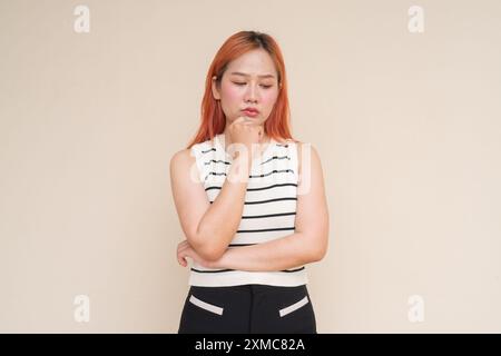 Ritratto di una donna asiatica stressata e triste che pensa sullo sfondo di Plain Studio Foto Stock