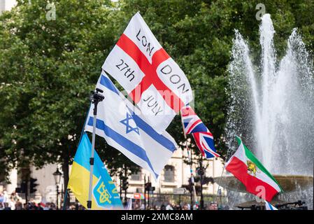 Trafalgar Square, Westminster, Londra, Regno Unito. 27 luglio 2024. I sostenitori di Tommy Robinson si riunirono nello Strand presso la Royal Courts of Justice per una marcia di protesta verso Trafalgar Square. I temi della protesta includono l'immigrazione, e una protesta avversaria organizzata da Stand Up to Racism si sta dirigendo verso la vicina Whitehall con 1000 agenti di polizia in servizio per scoraggiare gli scontri. Bandiere in Trafalgar Square, con bandiera inglese, bandiera israeliana, bandiera Ucraina e bandiera iraniana del leone e del sole, e data del 27 luglio Foto Stock