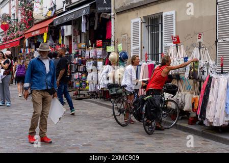 Parigi, Francia, 07.24.2024 turisti che cercano souvenir in una strada di Montmartre e un artista che cerca qualcuno da disegnare. Foto Stock