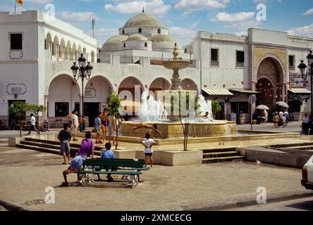 Tunisi, Tunisia. Moschea Sidi Mehrez (1675-92), Place Bab Souika. Bambini che giocano nella Fontana del quartiere. Ingresso Bab Souika a Medina sulla destra. Foto Stock