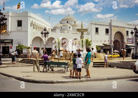 Tunisi, Tunisia. Moschea Sidi Mehrez (1675-92), Place Bab Souika. Bambini che giocano nella Fontana del quartiere. Ingresso Bab Souika a Medina sulla destra. Foto Stock