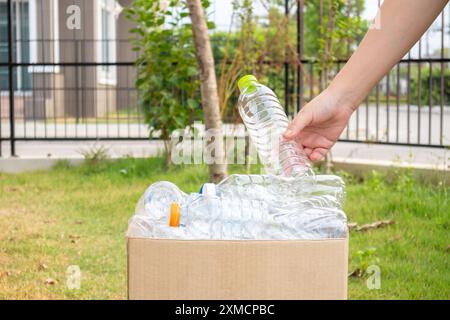 Tenere le mani e inserire i flaconi di plastica nella scatola marrone per rifiuti Foto Stock