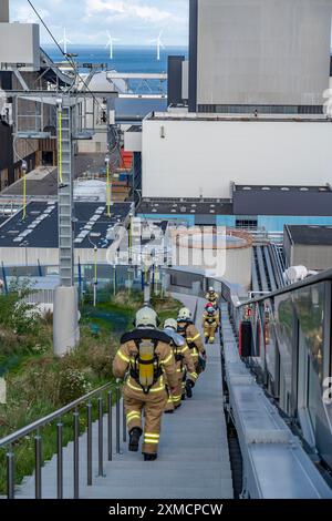 CopenHill, impianto di incenerimento dei rifiuti e pista da sci artificiale, vigili del fuoco sotto protezione respiratoria, allenamento di resistenza, sci con vista su Foto Stock