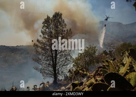 Si vede un elicottero cadere acqua durante l'incendio. Gli incendi in fiamme in Sicilia. Con l'aumento delle temperature e l'espansione della terraferma, l'isola del Mediterraneo soffre della crescente allerta di incendi più vicini alle città e ai centri turistici. Il 20 luglio un incendio si è diffuso da una valle vicina alla periferia di Castellammare del Golfo, nota località turistica. Le fiamme arrivarono vicino alle case, ma i vigili del fuoco e le guardie forestali lo controllarono in tempo. Foto Stock