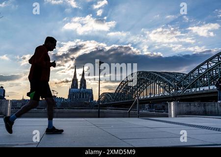 Panorama, skyline di Colonia, con la cattedrale e il ponte ferroviario, il ponte Hohenzollern, sul Reno, tramonto, jogger, Renania settentrionale-Vestfalia Foto Stock