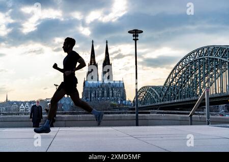 Panorama, skyline di Colonia, con la cattedrale e il ponte ferroviario, il ponte Hohenzollern, sul Reno, tramonto, jogger, Renania settentrionale-Vestfalia Foto Stock