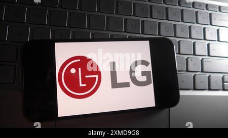 In questa illustrazione fotografica, il logo LG viene visualizzato su uno smartphone con sfondo della tastiera di un computer portatile. Foto Stock