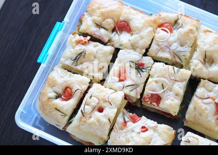 Pane italiano fatto a mano con verdure, tagliato in porzioni in un contenitore di plastica pronto per essere conservato. vista dall'alto. Pane a lievitazione naturale sano. Foto Stock