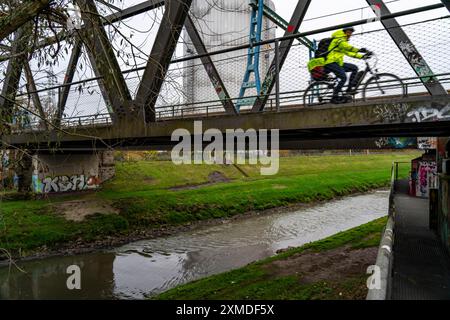 Il fiume Emscher, il fiume fognario, il vecchio ponte ferroviario, ora un sentiero pedonale e una pista ciclabile, un ponte per autobus e tram locali, a Oberhausen, nord Foto Stock