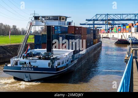 La nave da carico container entra nel bacino del porto del Logport, le gru a cavalletto nel centro di movimentazione container, il terminal container trimodale, nel Foto Stock