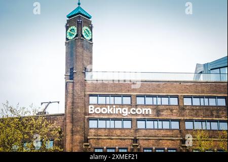 Ad Amsterdam, la moderna facciata in vetro della sede centrale del Booking.com riflette la vibrante energia della città. L'edificio sovrasta l'area, il suo lato Foto Stock