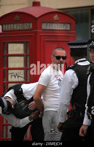 Londra, Inghilterra, Regno Unito. 27 luglio 2024. Gli agenti di polizia arrestano un uomo e lo allontanano dalla zona perché credevano che stesse cercando dei problemi mentre la parata passa da Regent Street. Il tema della sfilata di quest'anno è "giustizia e liberazione˜”, che rappresenta i diritti trans e la solidarietà con Palestina, Sudan, Haiti e Congo. Il sesto anniversario del 2024 segue un aumento dei tentativi di fare marcia indietro affermano gli organizzatori dei diritti umani della comunità transnazionale. Ciò include la recente politica del precedente governo conservatore in materia di "ideologia di genere”, che non deve più essere insegnata nelle scuole. Altrove, il Foto Stock