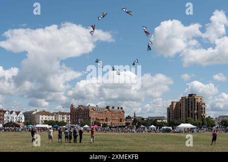 Festival degli aquiloni sul Southsea comune a Portsmouth. Gruppo di persone che volano aquiloni in formazione davanti all'hotel Queens. Luglio 2024. Foto Stock