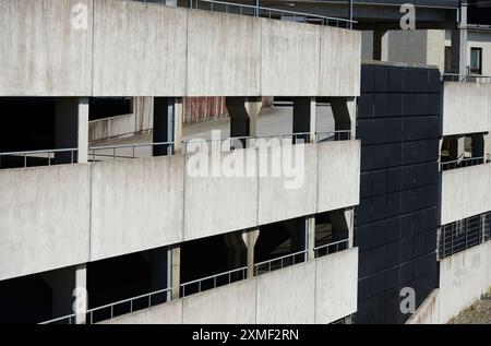 Questa immagine presenta una vista esterna di un garage a più piani. La struttura in cemento presenta il design grezzo e industriale tipico dell'arco urbano Foto Stock