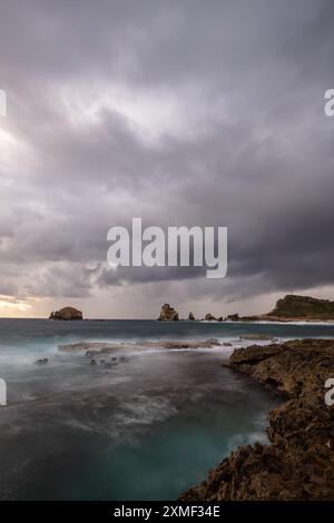 Stony Coast con formazioni di Sharp Rock in A Bay in the Sea. Alba piovosa, atmosfera suggestiva. Pointes Des Colibris a grande Terre, Guadalupa, Fren Foto Stock