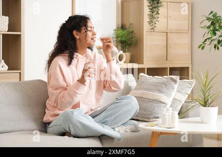 Giovane donna afroamericana che prende l'olio di pesce a casa Foto Stock