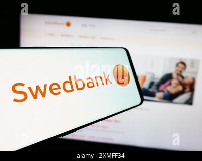 Telefono cellulare con logo della società svedese di servizi finanziari Swedbank AB davanti al sito web aziendale. Mettere a fuoco la parte centrale sinistra del display del telefono. Foto Stock