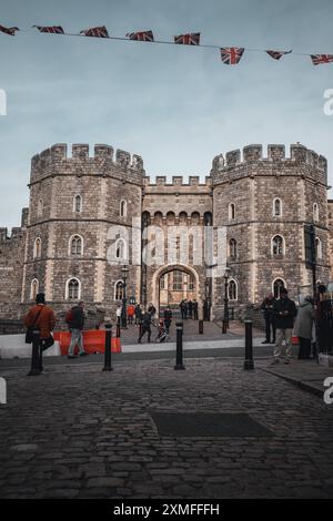 Windor Castle, UK - 16 ottobre 2023: Un castello in pietra con un grande ingresso ad arco. La gente cammina di fronte al castello su una strada acciottolata. Foto Stock