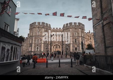 Windor Castle, UK - 16 ottobre 2023: Vista su un vecchio edificio in pietra con una grande porta ad arco. La gente passa e ci sono bandiere britanniche appese Foto Stock