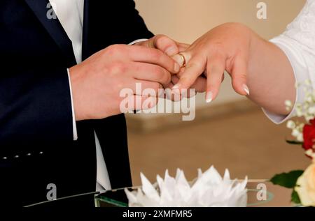 Lo sposo posiziona la banda nuziale della sposa sul dito dell'anello della sposa. La cerimonia nuziale del fidanzamento. Foto Stock